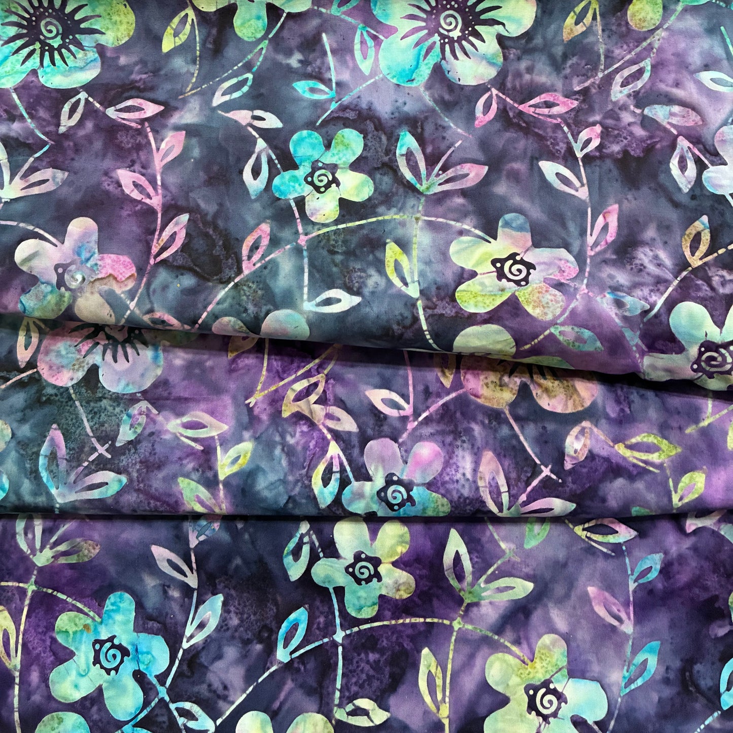 Floral fabric with green and pink flowers on a purple background