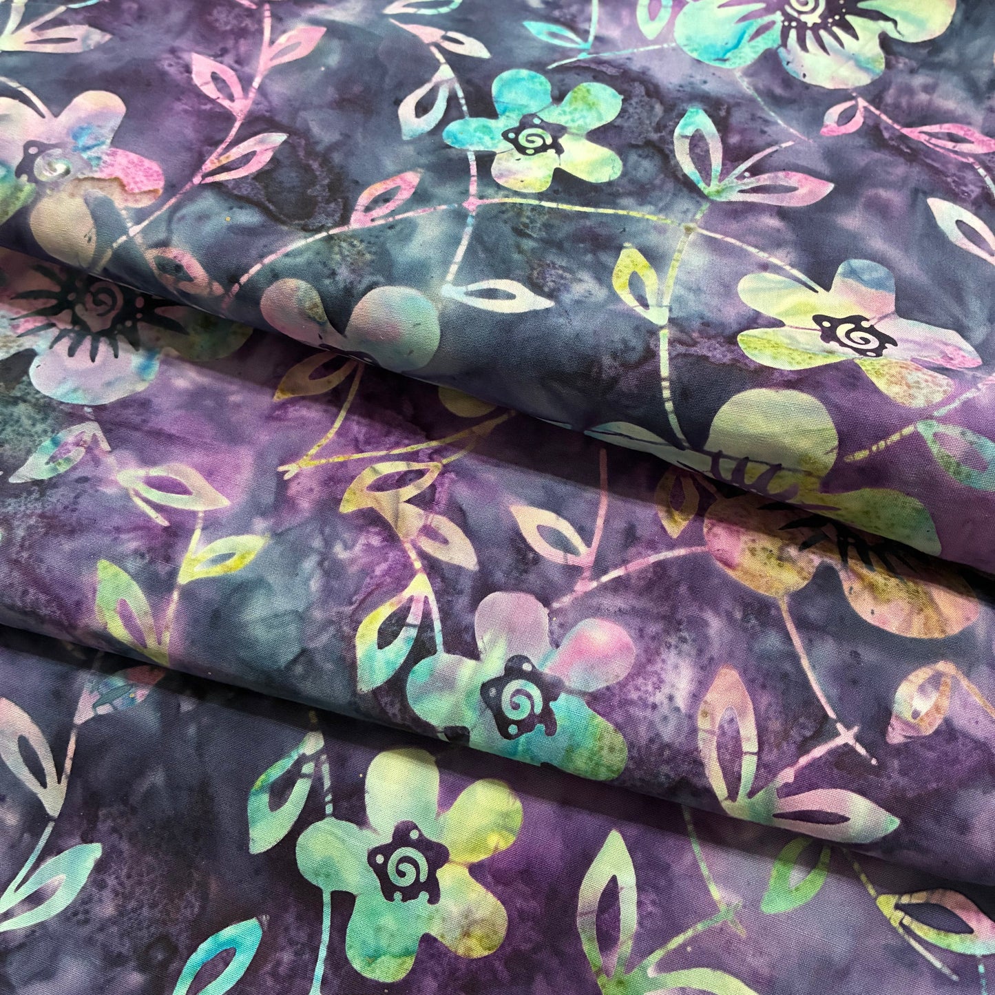 Floral fabric with green and pink flowers on a purple background
